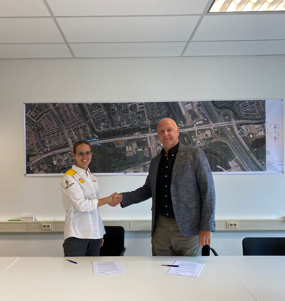Foto met medewerker Shell en gemeente Zaanstad die elkaar handschudden na tekenen overeenkomst